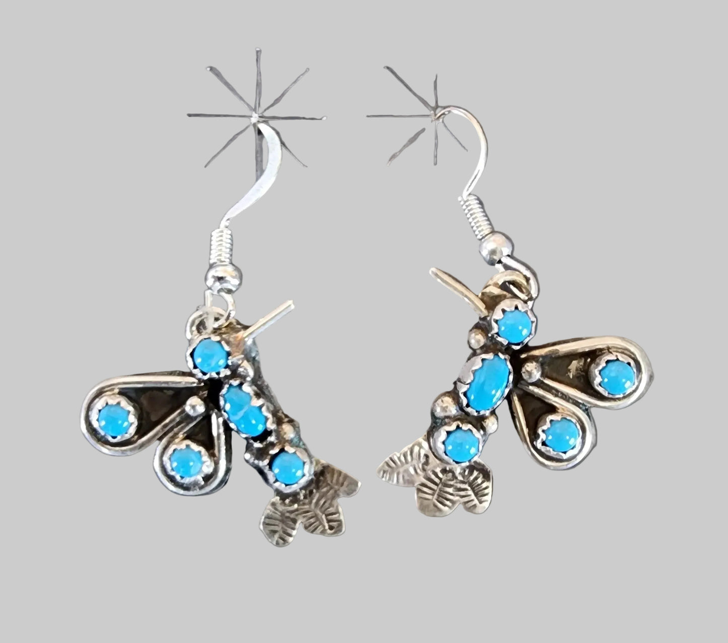 Silver earrings with blue stones on a gray card, with a price tag showing $110.00.