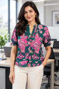 A women's short-sleeve blouse with a vibrant pink and green floral print.